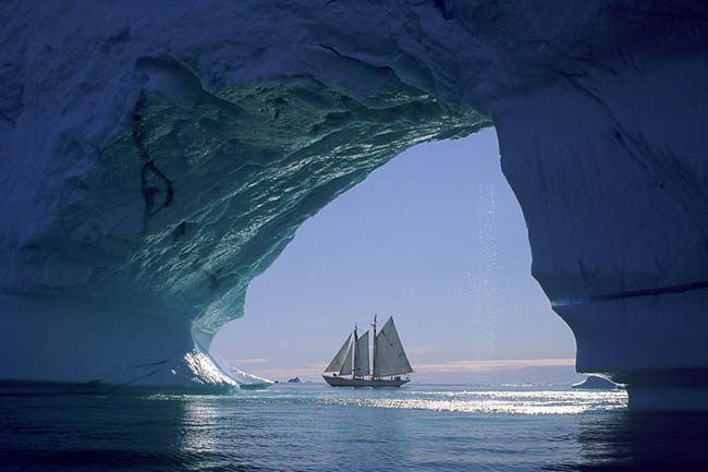 Sailboat-seen-through-huge-iceberg-cave